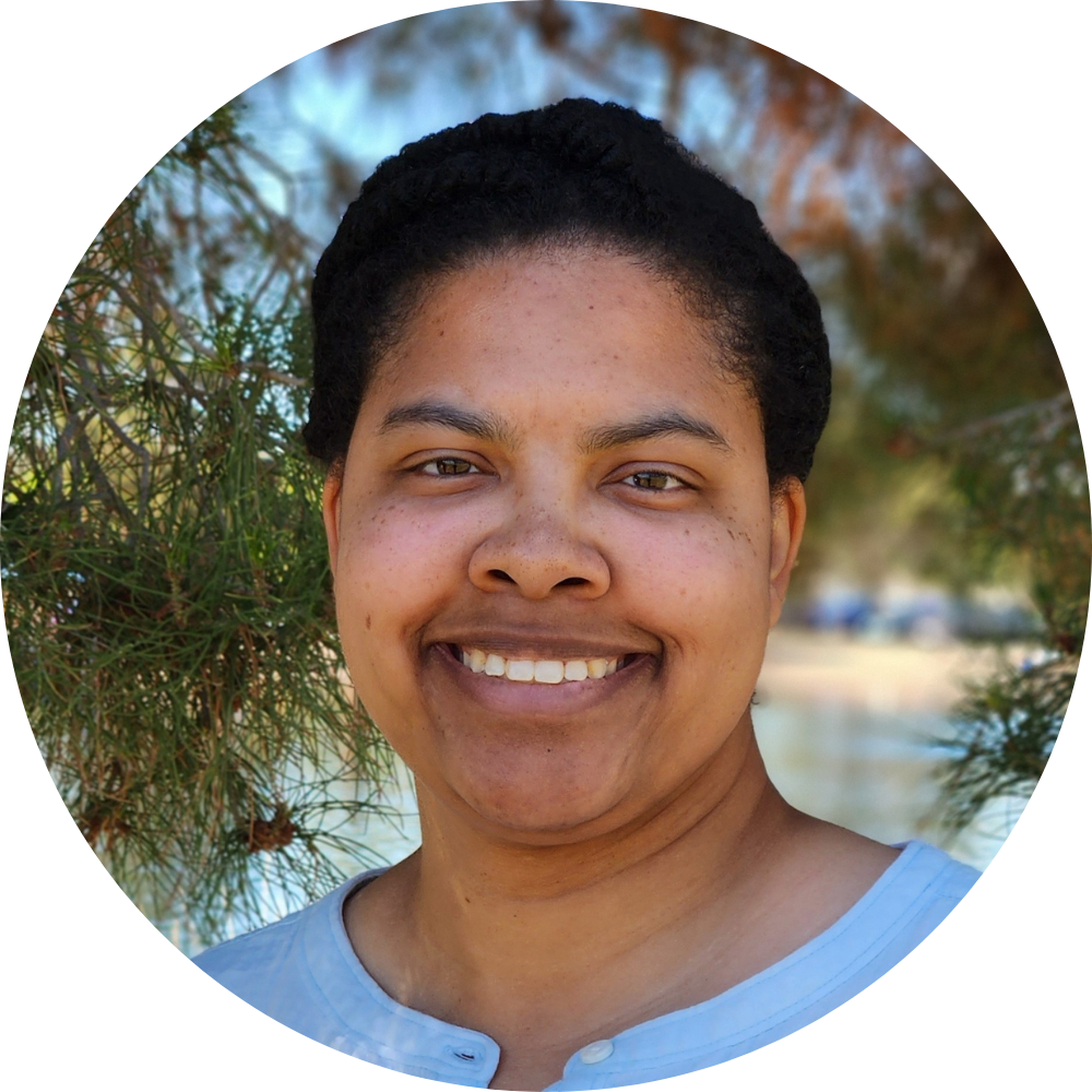 Headshot of Kaitlyn Mallett, Ph.D., with dark green leaves and water visible in the background, credit to Mariah Mallett